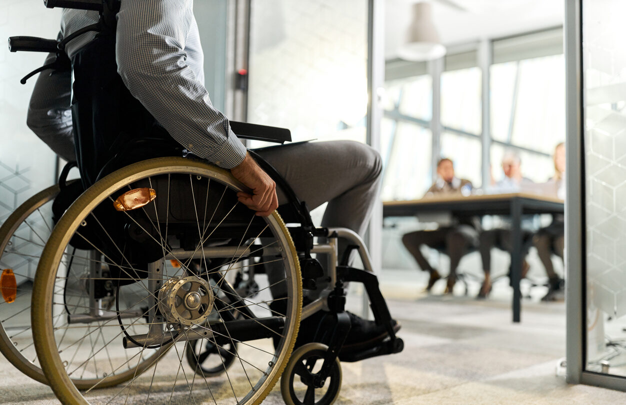 Unrecognizable male candidate in a wheelchair entering the office for a job interview.